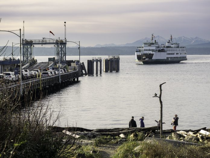 Folks walk the beach as the Washington State ferry comes in. Cars wait on the dock.