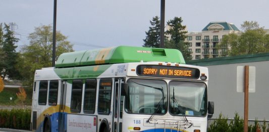 A white, blue, and green bus runs with a not in service sign.