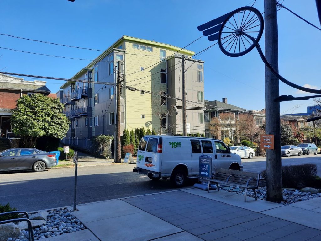 A four story building includes simple small balconies and a yellow and gray exterior.