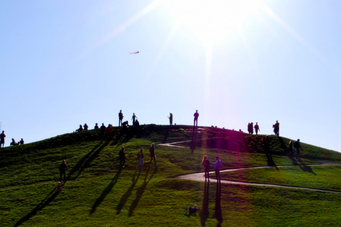 a photo of people standing on a green hill under a blue sky