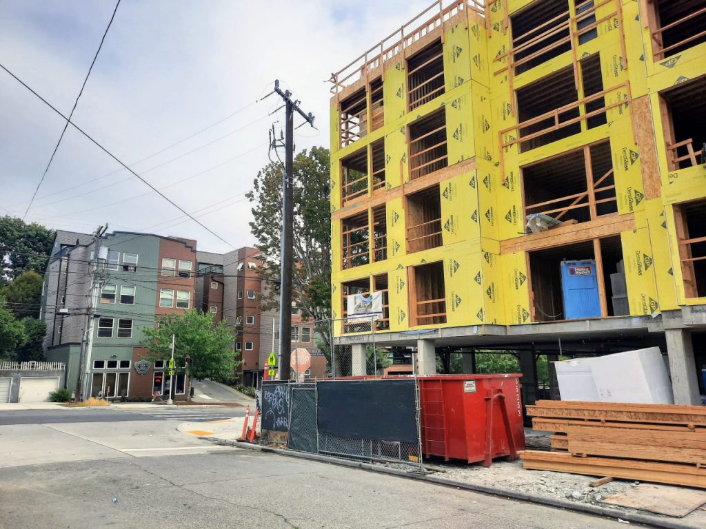 A five story building with yellow insulation before siding is added.