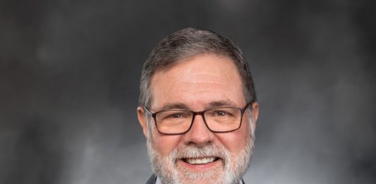 A middle aged man with glasses and a grey beard.