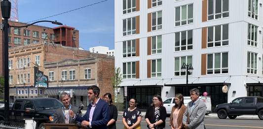 Spokane Council Member Zack Zappone and others in front of a new Spokane apartment building.