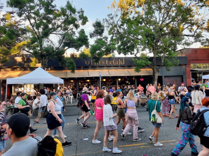 The LGBTQ parade takes over Broadway in front of the Olmstead bar patio.