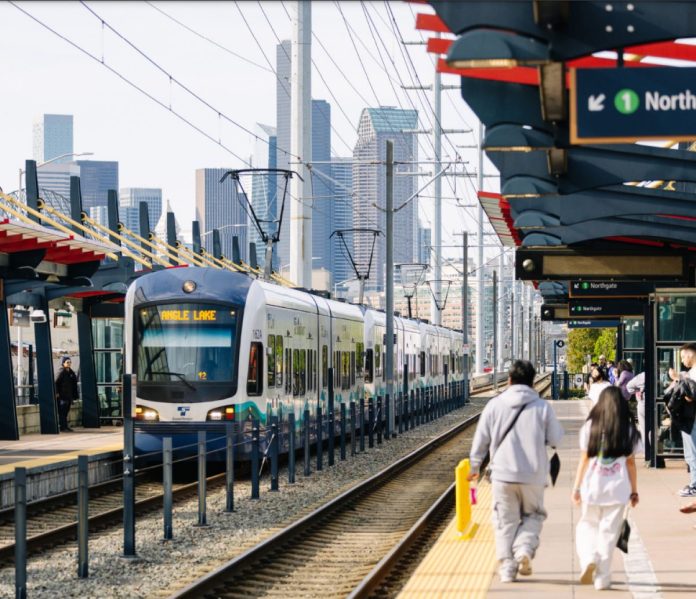 Two riders walked down the platform with the Seattle skyline in the distance.