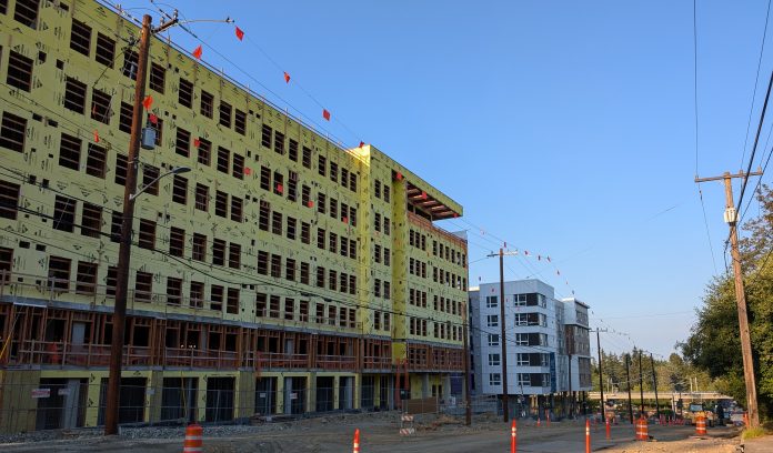 An 8 story building under construction near a similarly sized building that is already completed.