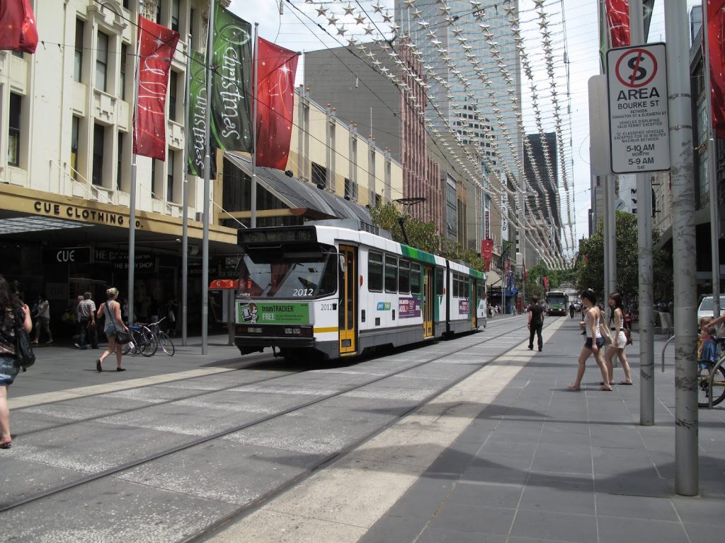 A tram on a busy city street with pedestrians.