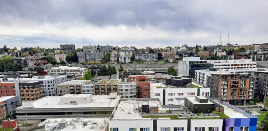 An rooftop view of rows of midrise apartments in South Lake Union with Capitol Hill in the distance.