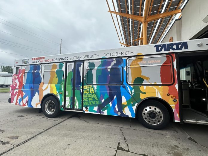 The bus wrap ad shows silhouettes of people walking and rolling.