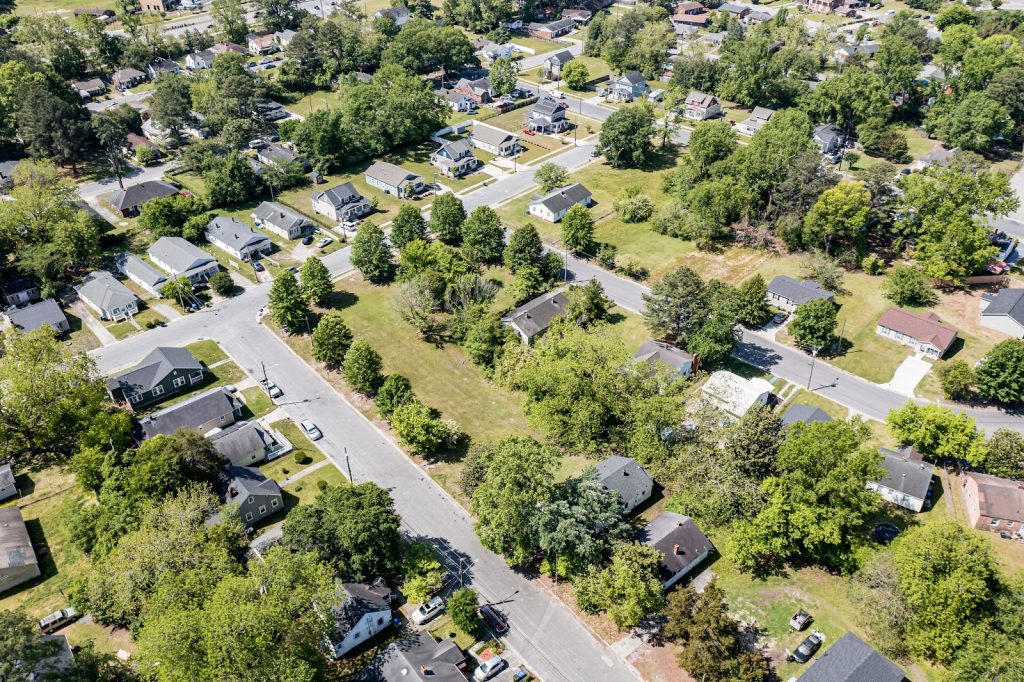 An aerial phot shows low density housing and lots of trees and grass.