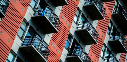 A tall red residential building with balconies.