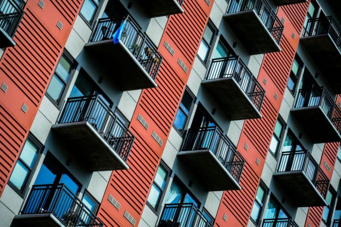 A tall red residential building with balconies.