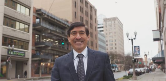 Mungia poses in a suit on a downtown Tacoma street.