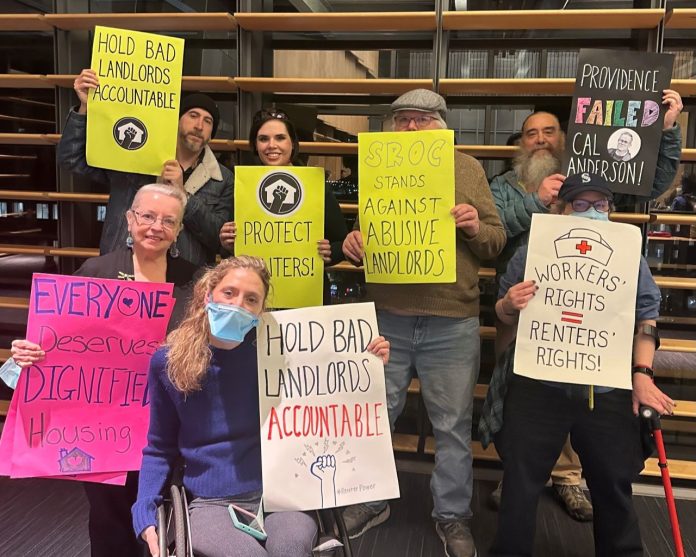 Tenants hold signs saying "hold bad landlords accountable" and "everyone deserves dignified housing" and "SROC stands against abusive landlords" and "workers rights = renters' rights"