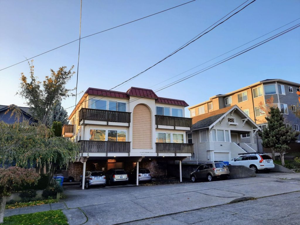 A two story apartment building is cantilevered over surface parking in what is colloquially called a "dingbat."