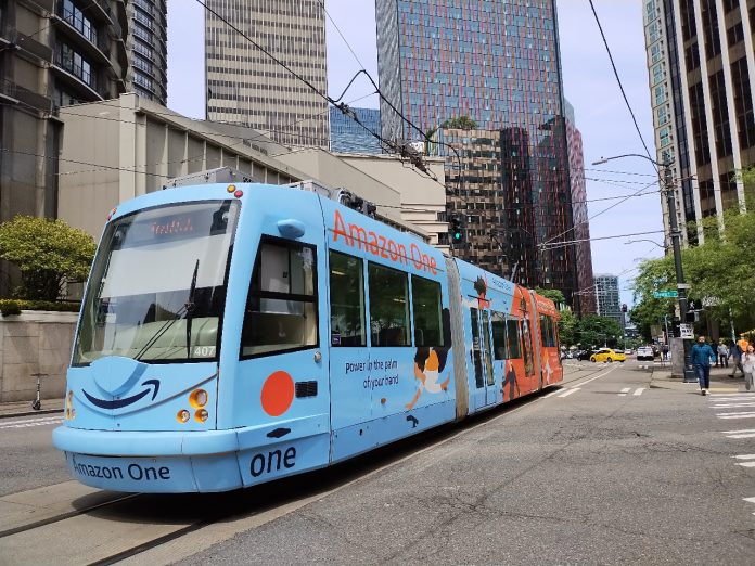 A light blue streetcar tram on Westlake Avenue in South Lake Union with office buildings towering above.