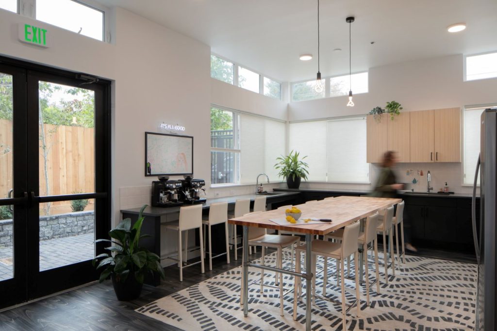 A large kitchen with a dining table in the middle looks out on a patio.