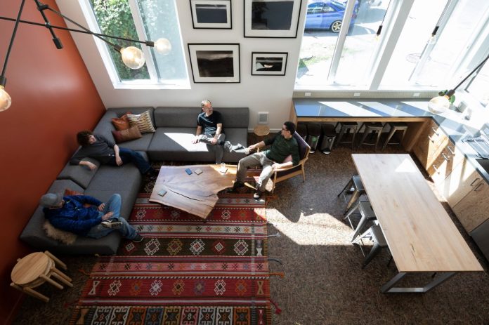 Four residents sit in a L couch in a lounge well-lit by natural light.