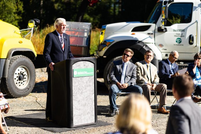 Roger Millar standing at a podium for a photo op