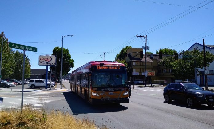 An E Line bus heads northbound on Aurora Avenue N near Green Lake on a sunny day.