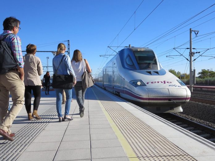 A group of a half dozen passengers walk to board a train