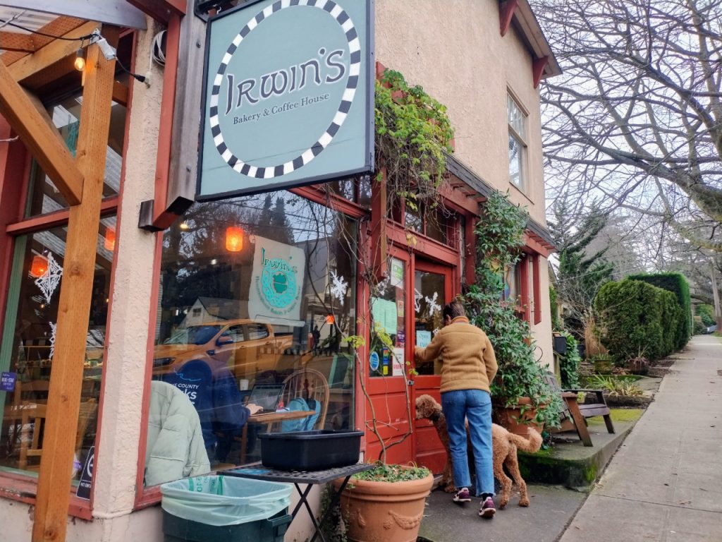 A patron grips the front door at Irwin's neighborhood cafe in leafy Wallingford. Customers fill the window seats inside.