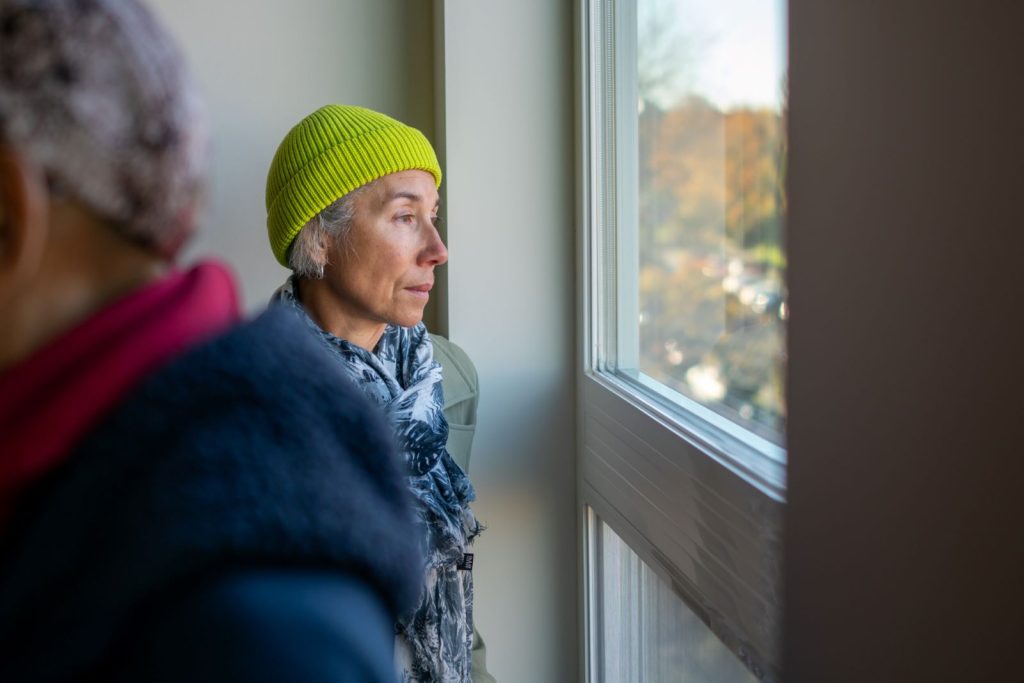 Winkler-Chinw wears a lime green stocking hat and looks pensively out the window.