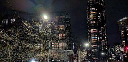 Teku Tavern and the view east up Denny Way with skyscrapers shining in the night in the background.