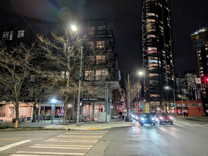 Teku Tavern and the view east up Denny Way with skyscrapers shining in the night in the background.