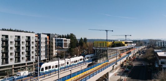 A train in testing arriving at Downtown Redmond, with buildings under construction behnind