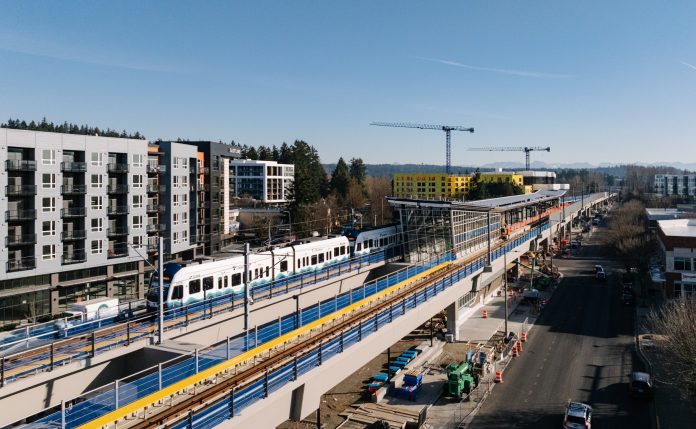 A train in testing arriving at Downtown Redmond, with buildings under construction behnind