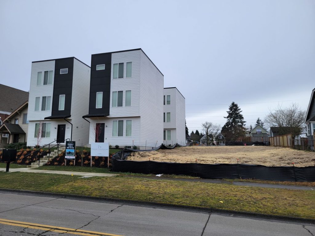 A three-story fourpack townhome next to an empty lot. 