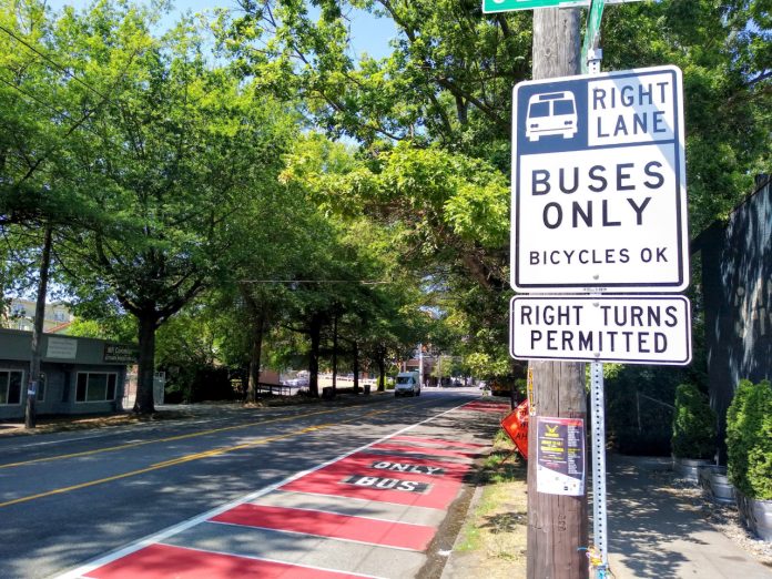 A red bus lane in the Rainier Valley with a sign reading "buses only, right turns permitted"