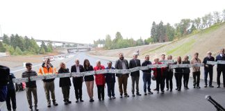 A long line of legislators and other leaders standing on a new segment of SR 509 before a ribbon is cut