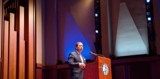 Harrell grips a lectern and wears a somber look during his speech at Benaroya Hall.