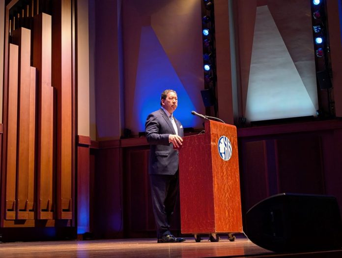 Harrell grips a lectern and wears a somber look during his speech at Benaroya Hall.