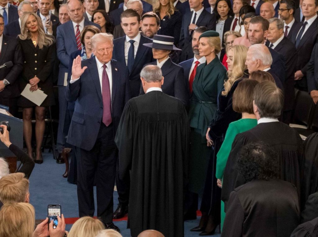 Trump raises his hand to complete the oath of office.