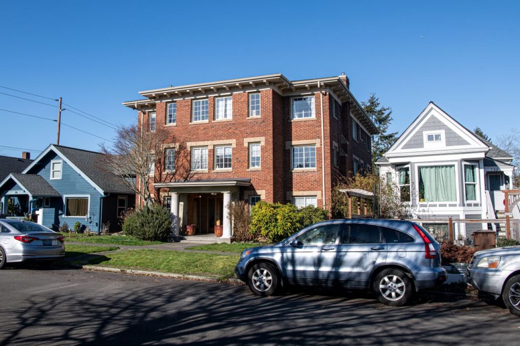 A brick apartment building is flanked by two single family homes.